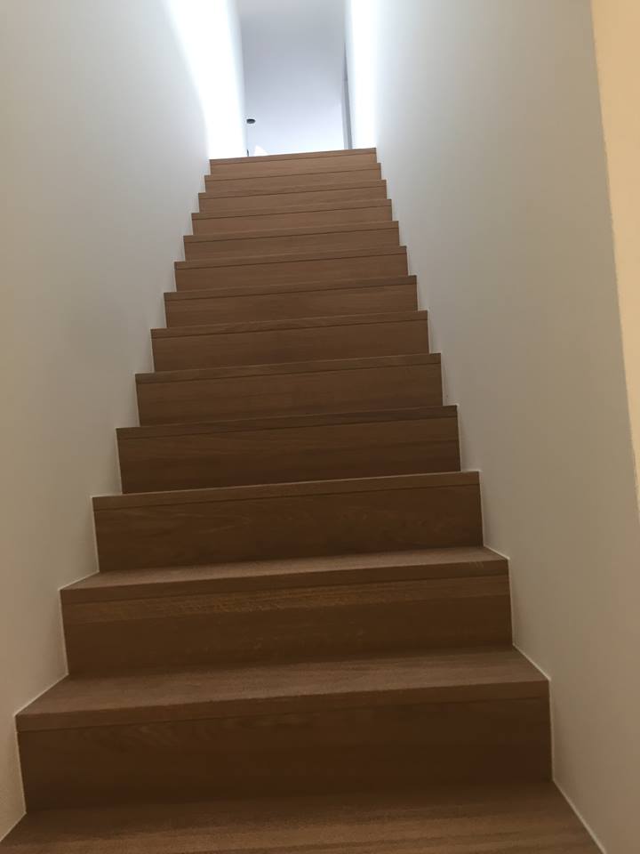 Modern afgewerkte houten trap met helderwitte wanden